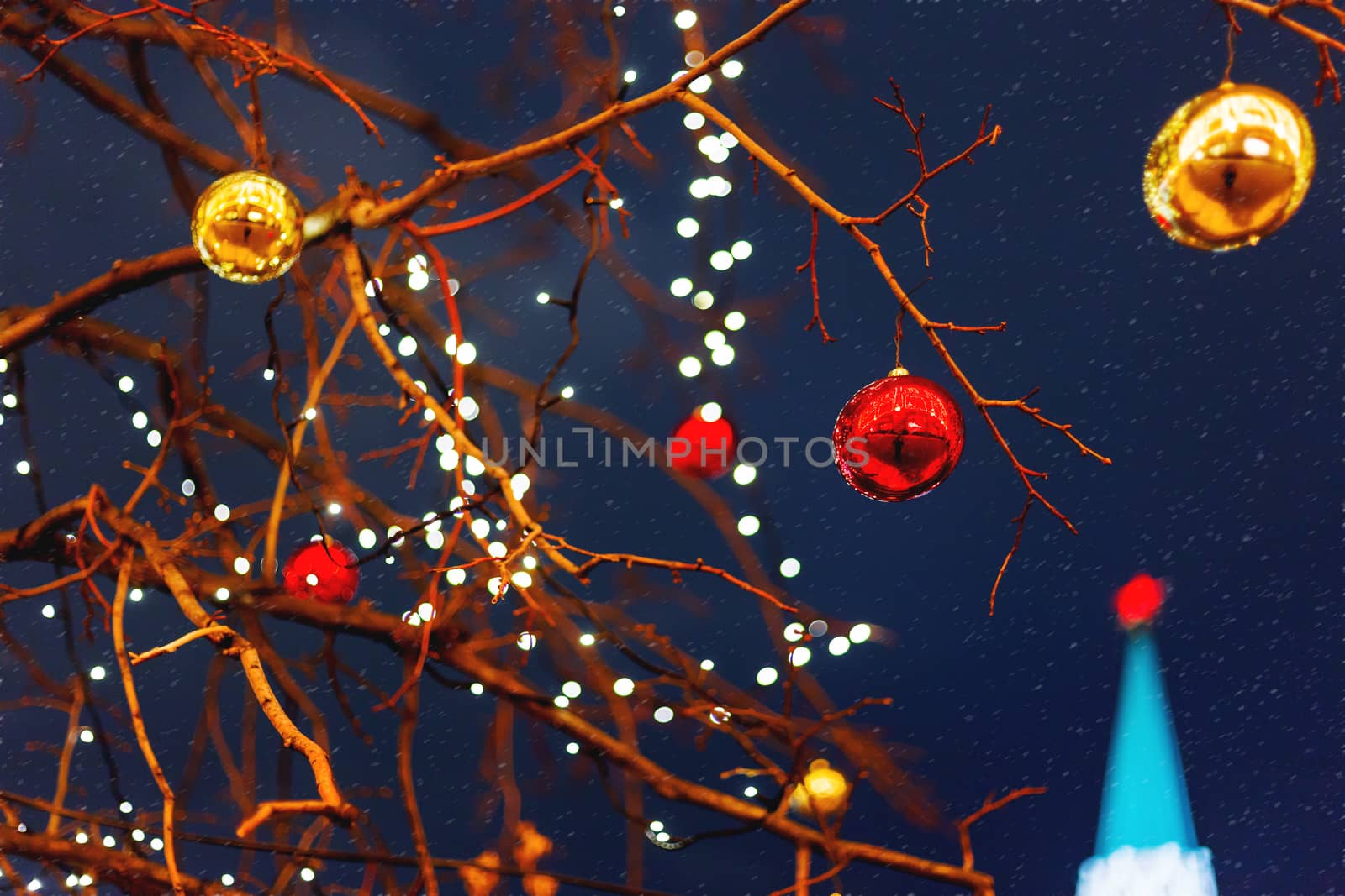 Streets of Moscow decorated for New Year and Christmas celebration. Tree with bright red and yellow balls. The St.Nicholas (Nikolskaya) tower of Kremlin on the background. Russia.