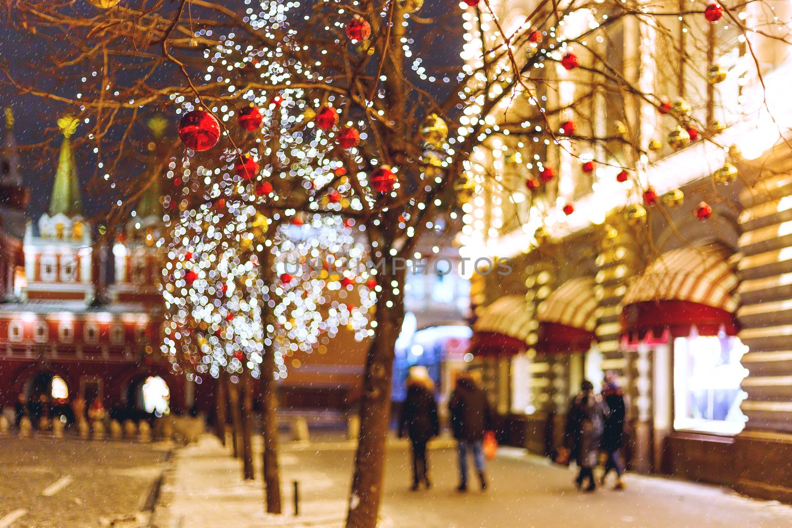 Streets of Moscow decorated for New Year and Christmas celebration. Tree with bright red and yellow balls. Buildings with light bulbs.