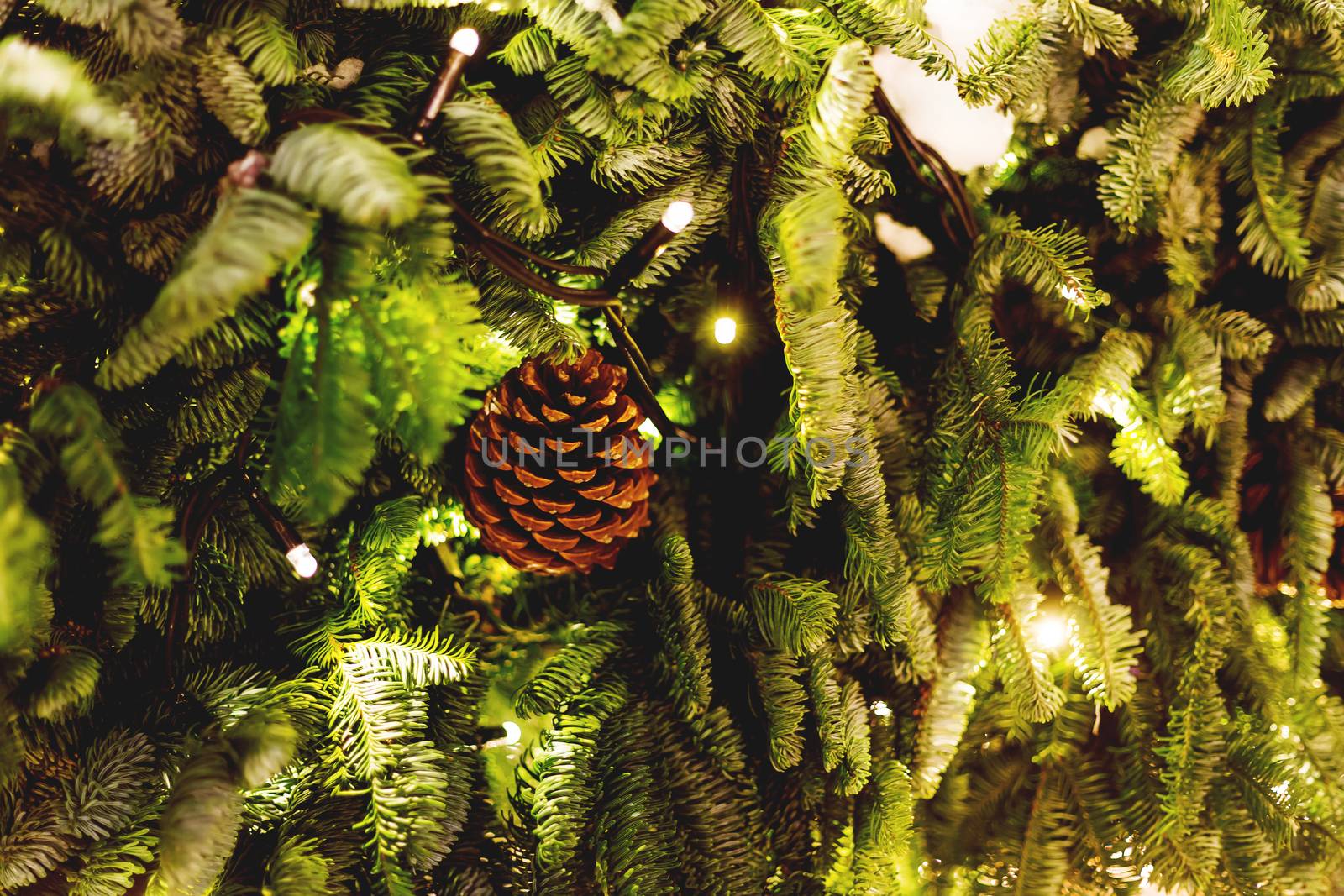 Fir tree decorated with cones and light bulbs for Christmas and New Year celebration. Natural winter background.