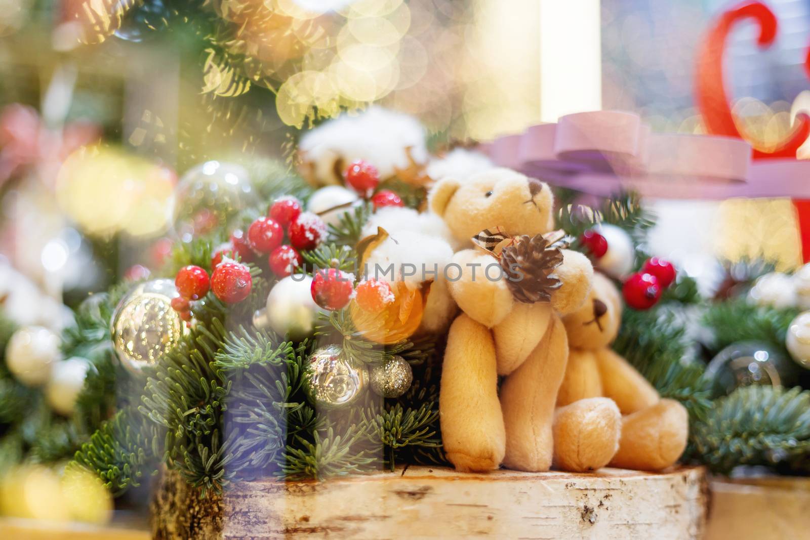 Christmas and New Year background with fir trees and toy bears - decoration made of branches with light bulbs and bright balls.