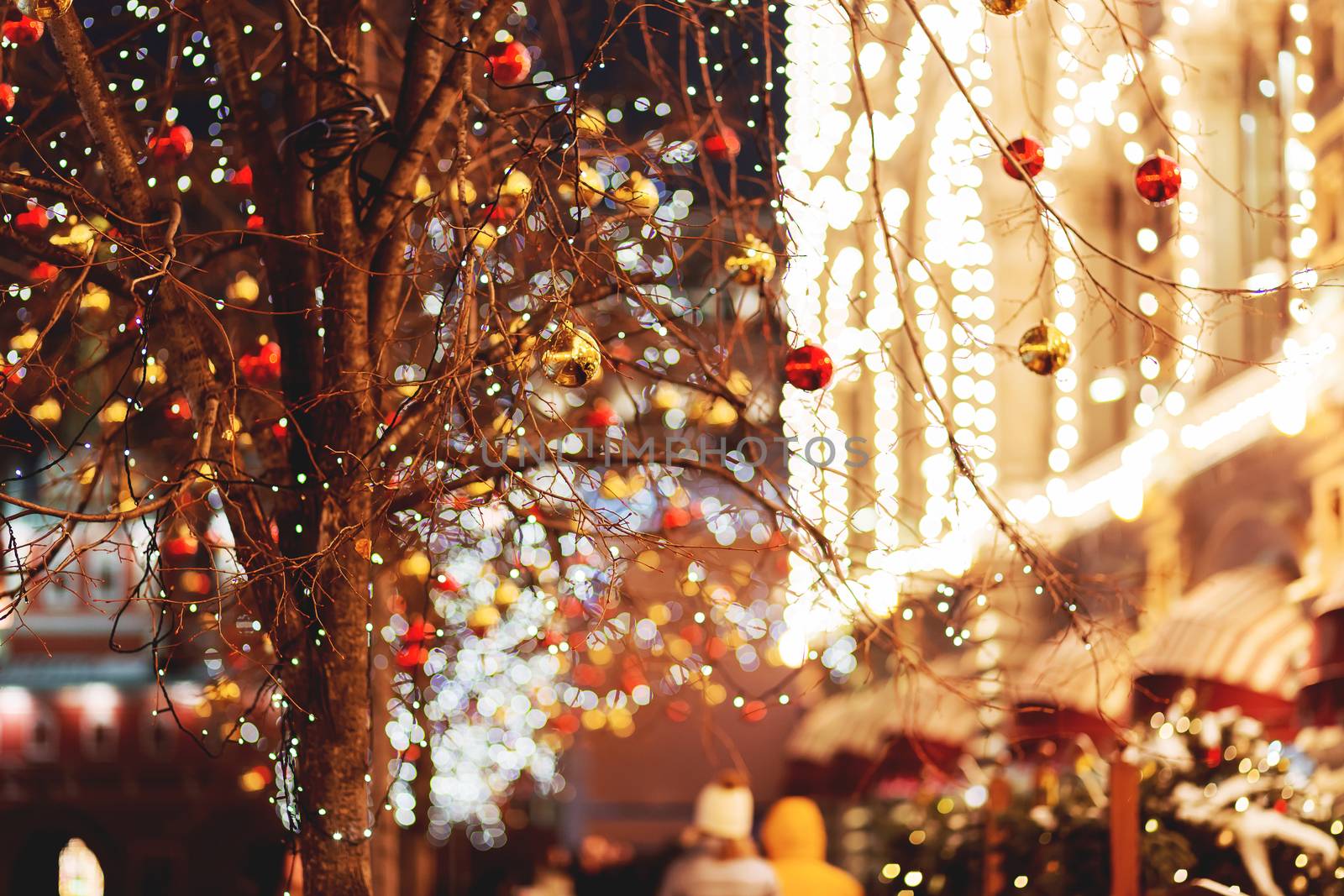 Streets of Moscow decorated for New Year and Christmas celebration. Tree with bright red and yellow balls. Buildings with light bulbs. Russia.