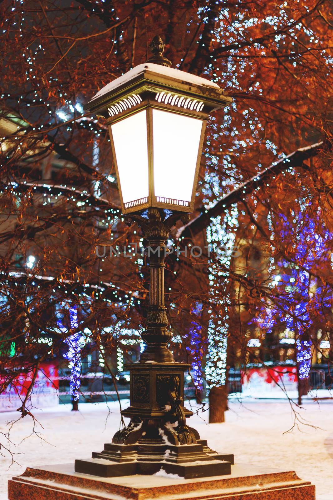 Old fashioned lantern on street. Trees are decorated for New Year and Christmas celebration. Moscow, Russia. by aksenovko