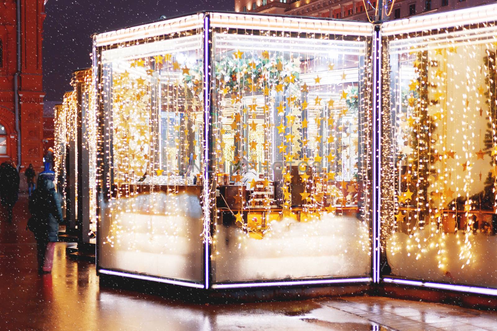 Streets in the historical center of Moscow decorated for New Year and Christmas celebration. Cafe windows with bright yellow stars and light bulbs. Russia.