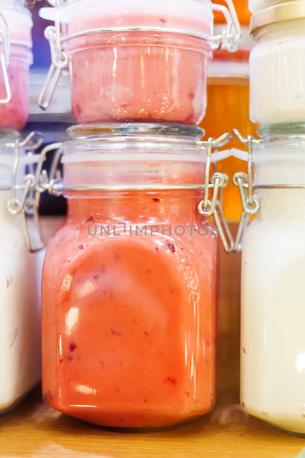 Holiday fair. Jars of creamy honey with berries glowing in garlands of lighting bulbs.