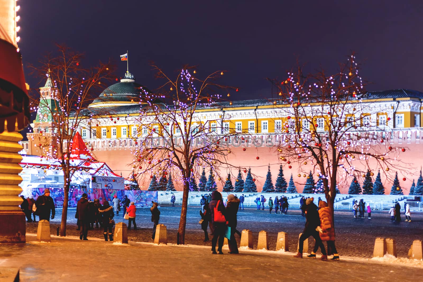 Streets of Moscow decorated for New Year and Christmas celebration. Tree with bright red and yellow balls. Buildings on Red Square with light bulbs.