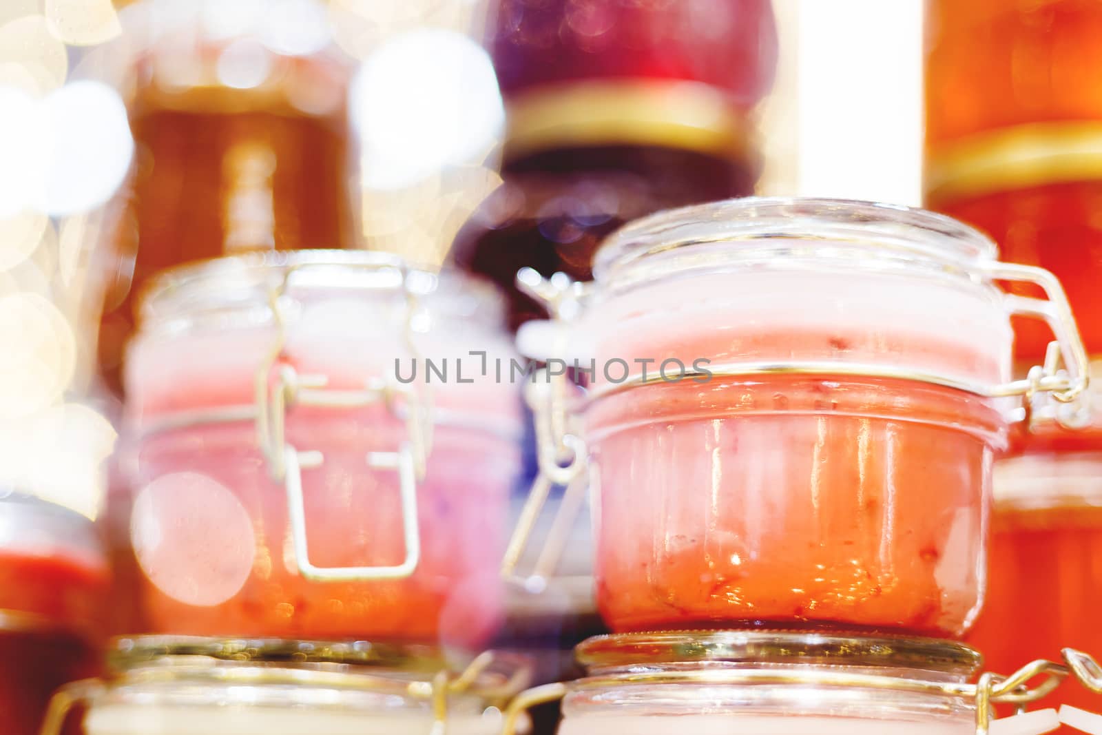 Holiday fair. Jars of creamy honey with berries glowing in garlands of lighting bulbs.
