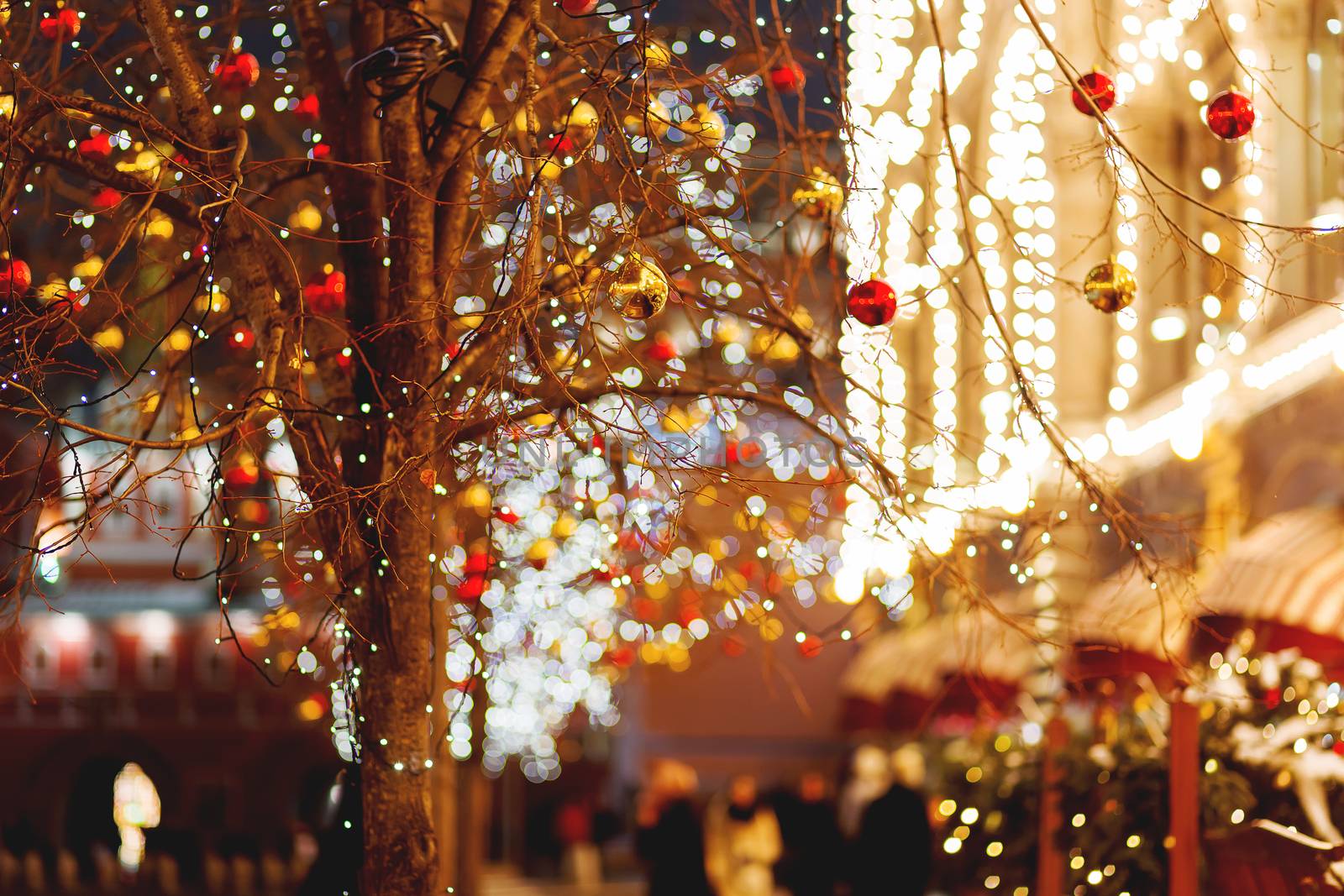 Streets of Moscow decorated for New Year and Christmas celebration. Tree with bright red and yellow balls. Buildings with light bulbs. Russia.