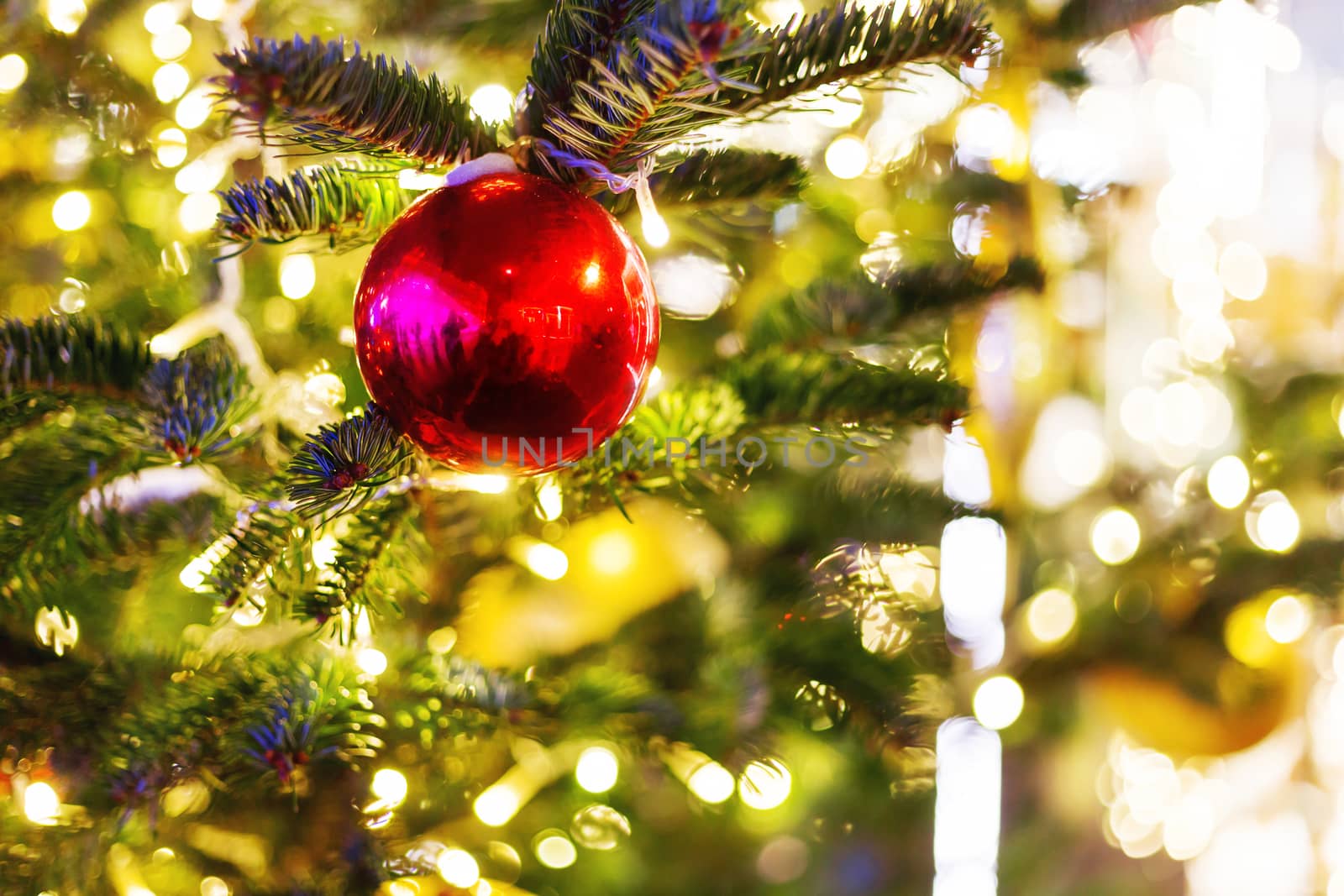 Christmas and New Year background with fir tree branches and decorations - light bulbs and bright red ball.