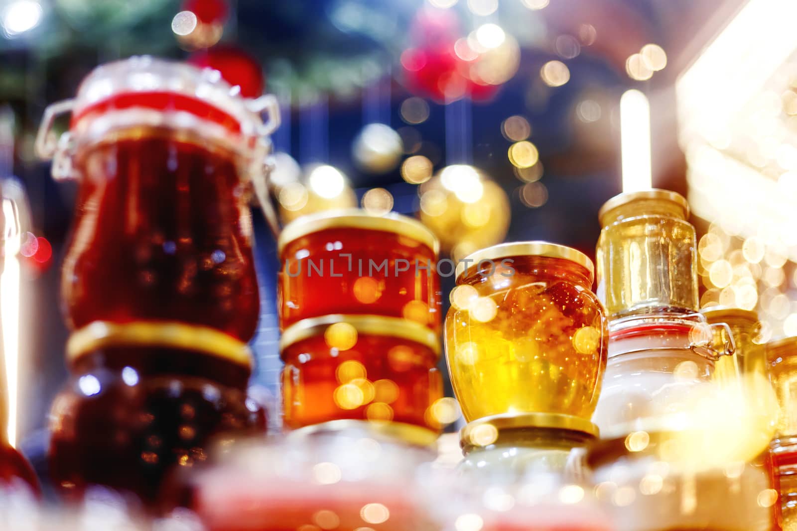 Holiday fair. Jars of honey glowing in garlands of lighting bulbs.