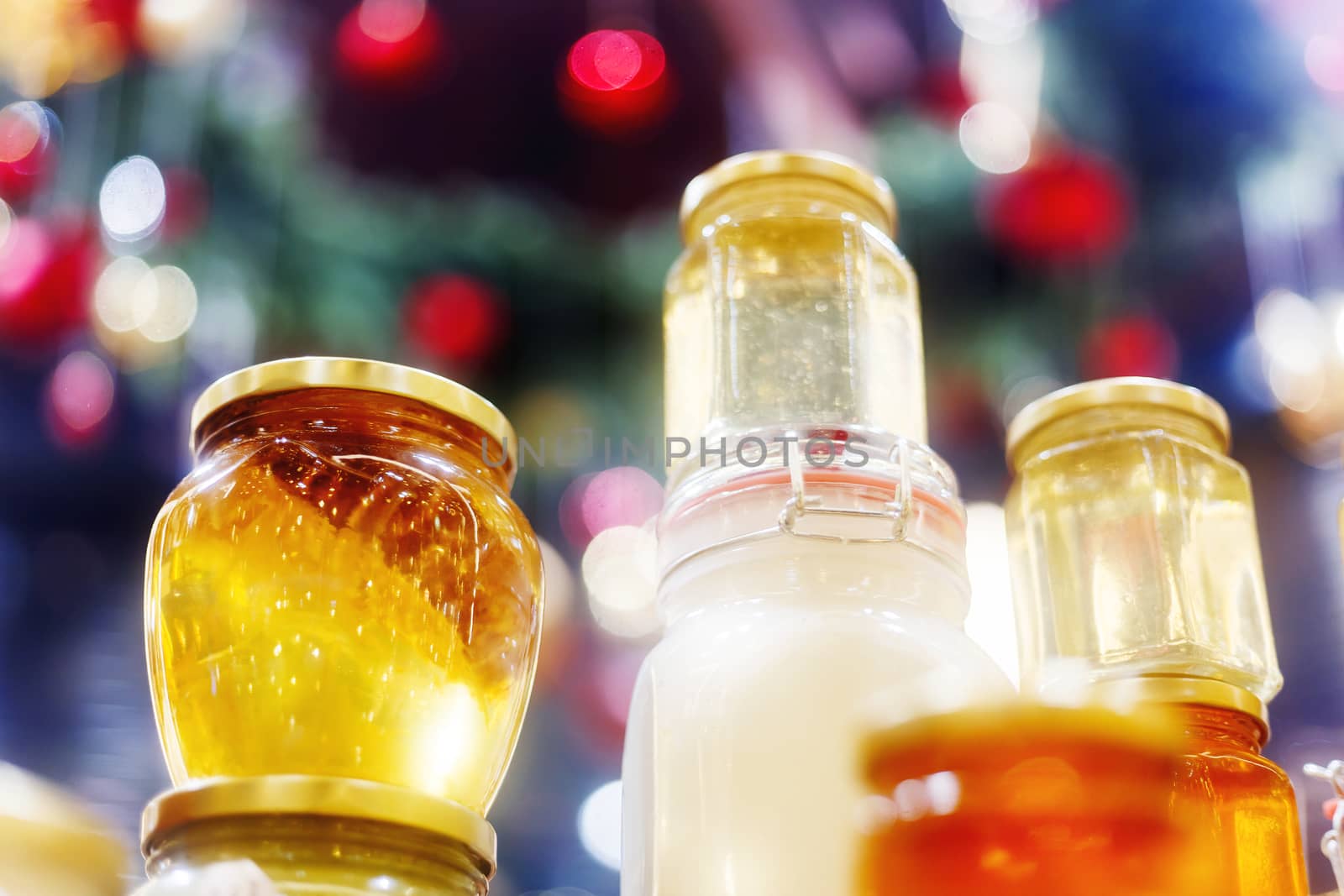 Holiday fair. Jars of honey glowing in garlands of lighting bulbs.
