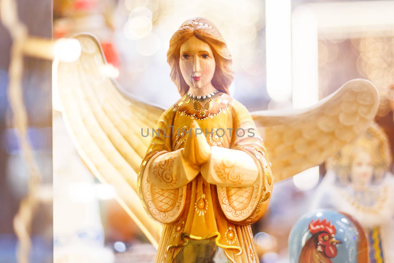 Wooden carved angel, Christmas holiday decoration. Bright light bulbs on background.