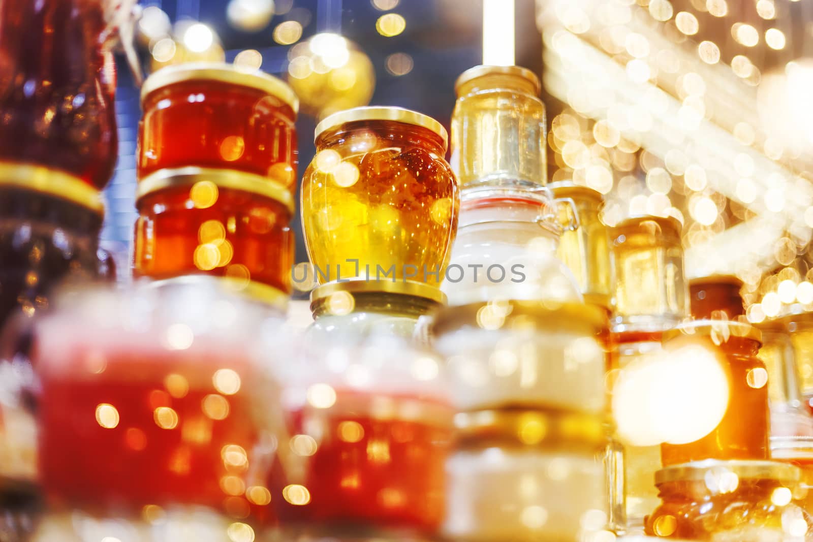 Holiday fair. Jars of honey glowing in garlands of lighting bulbs.
