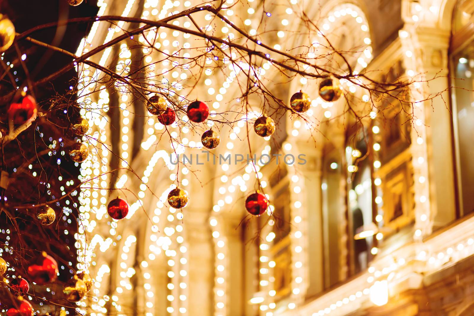 Streets of Moscow decorated for New Year and Christmas celebration. Tree with bright red and yellow balls. Buildings with light bulbs. Russia.