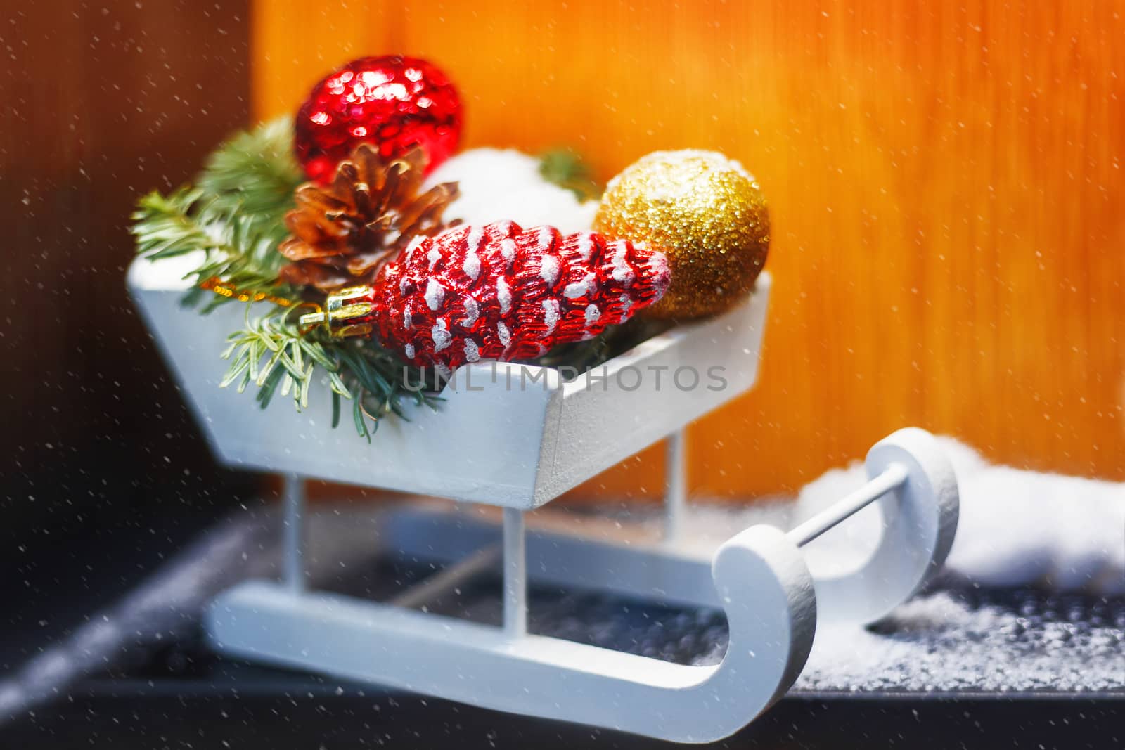 Christmas and New Year decorations - white wooden sledge with bright sparkling balls and fir tree branches.