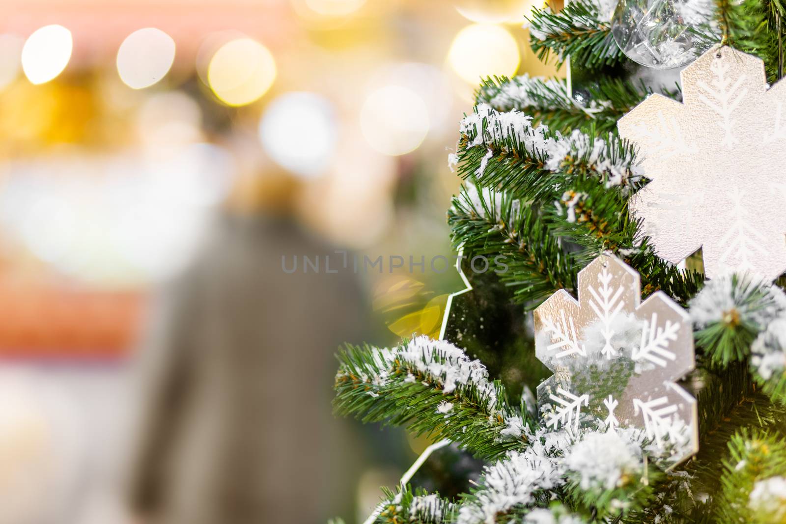 Fir tree decorated with shiny snow flakes and light bulbs for Christmas and New Year celebration.