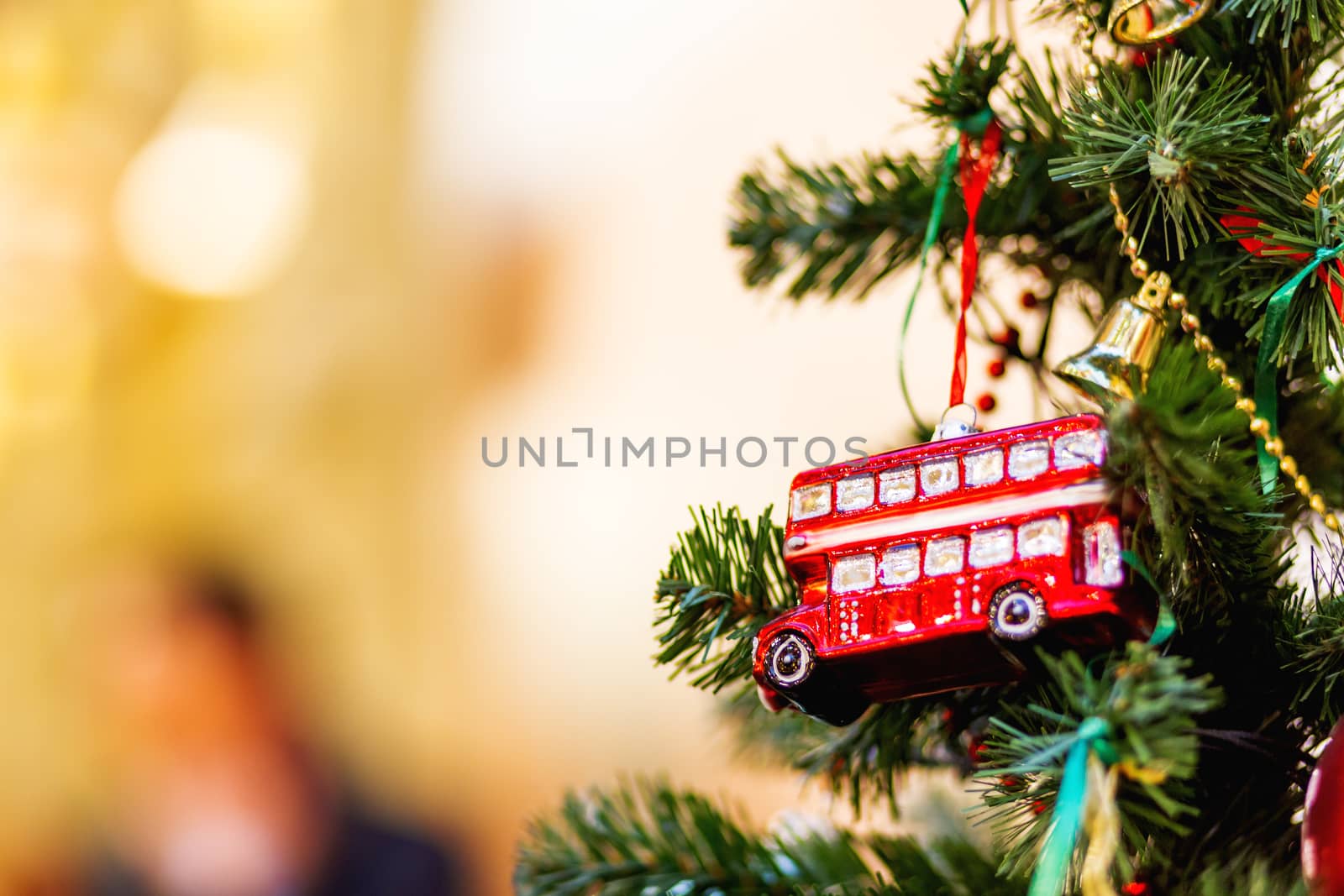 Fir tree decorated with toy double decker bus and light bulbs for Christmas and New Year celebration.