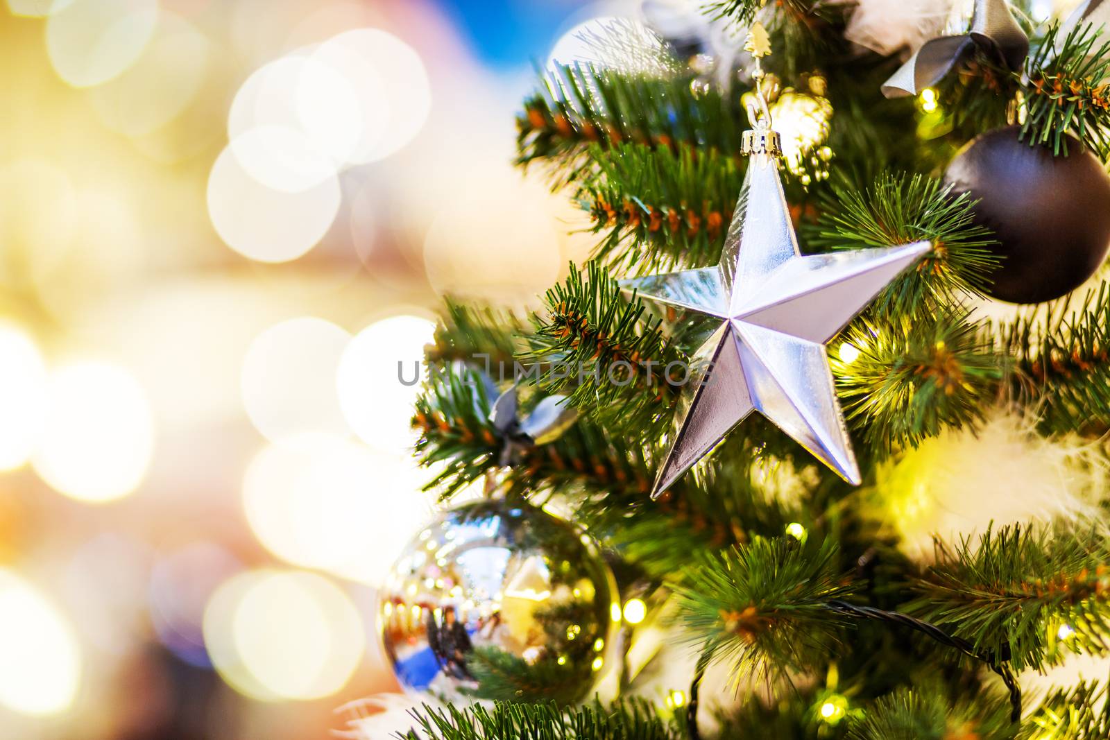 Fir tree decorated with shiny balls, star and light bulbs for Christmas and New Year celebration.