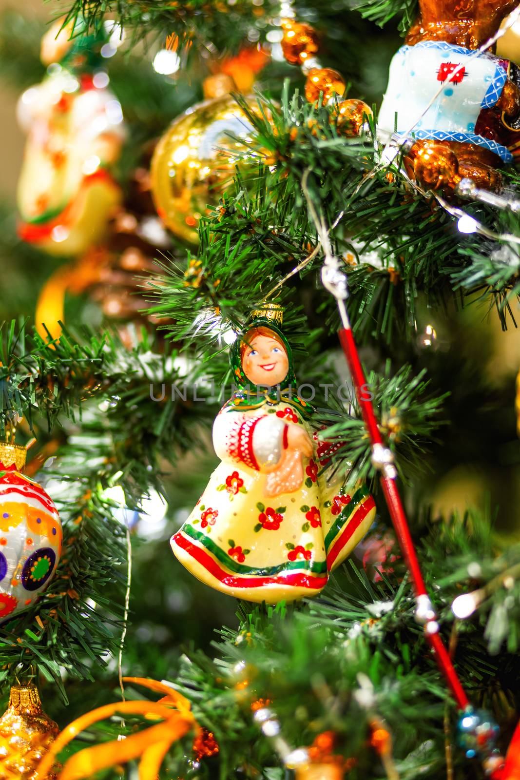 Fir tree decorated with shiny old fashioned toys and light bulbs for Christmas and New Year celebration.