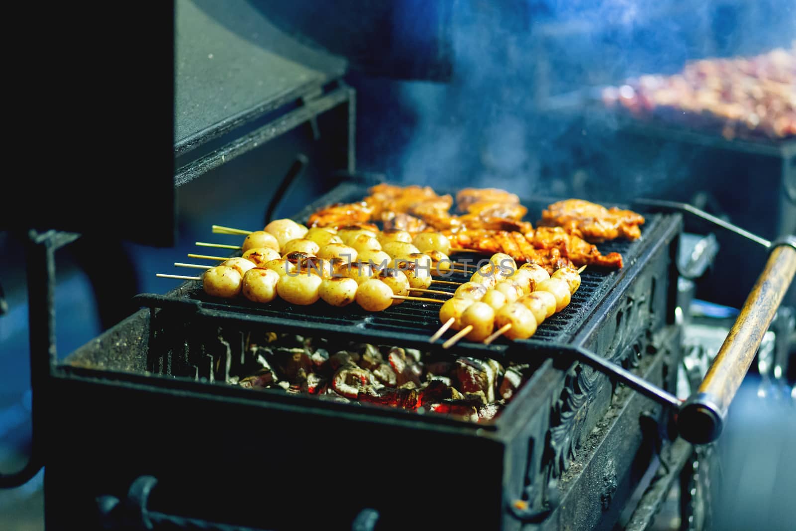 Barbecue skewer spinning on the grill. Fresh steaming meat and potato BBQ. Street cart with grill.