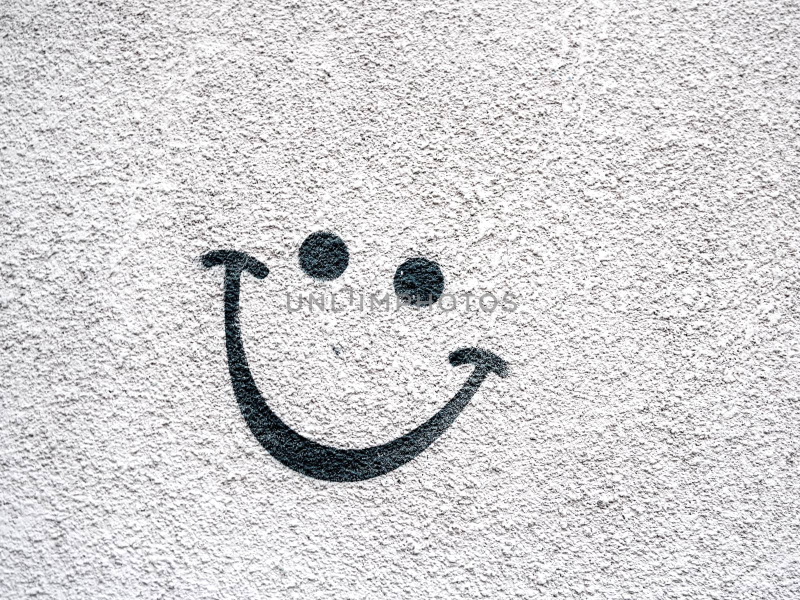 Smiling face on concrete surface. Eyes and lips drawn on outdoor wall.