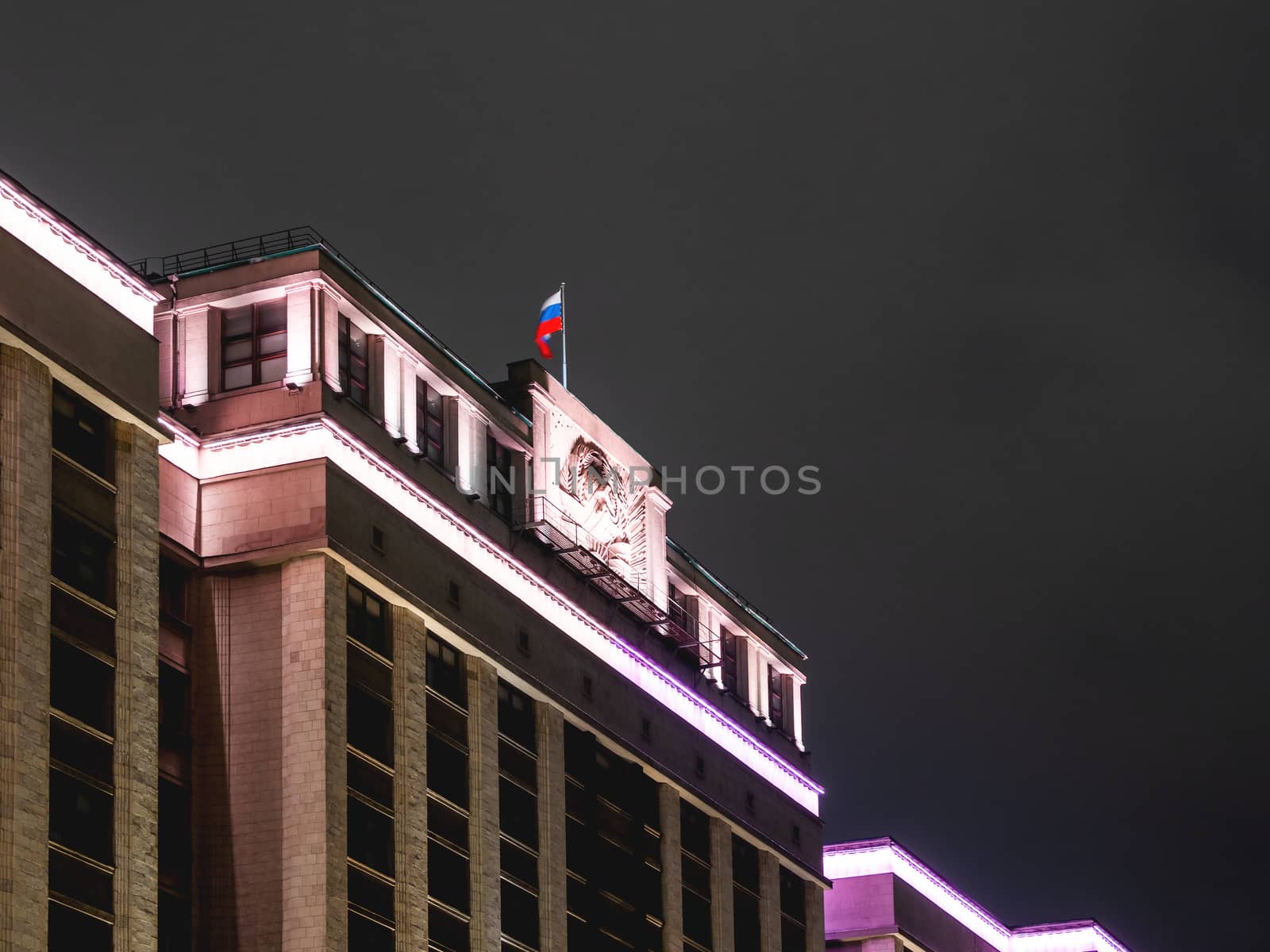 Building of State Duma of Russia. Illuminated top of building with national flag.
