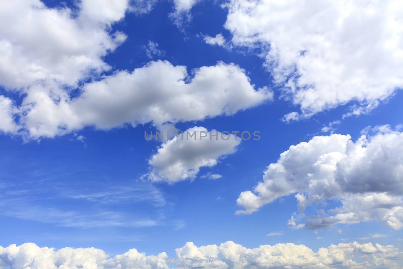 Blue sky background with the texture of white and fluffy, fun clouds.