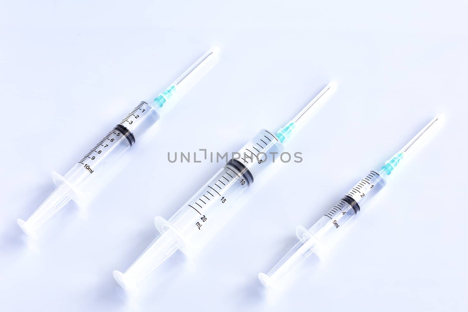 Several different syringes on a light smooth table, ready to use. by Sergii