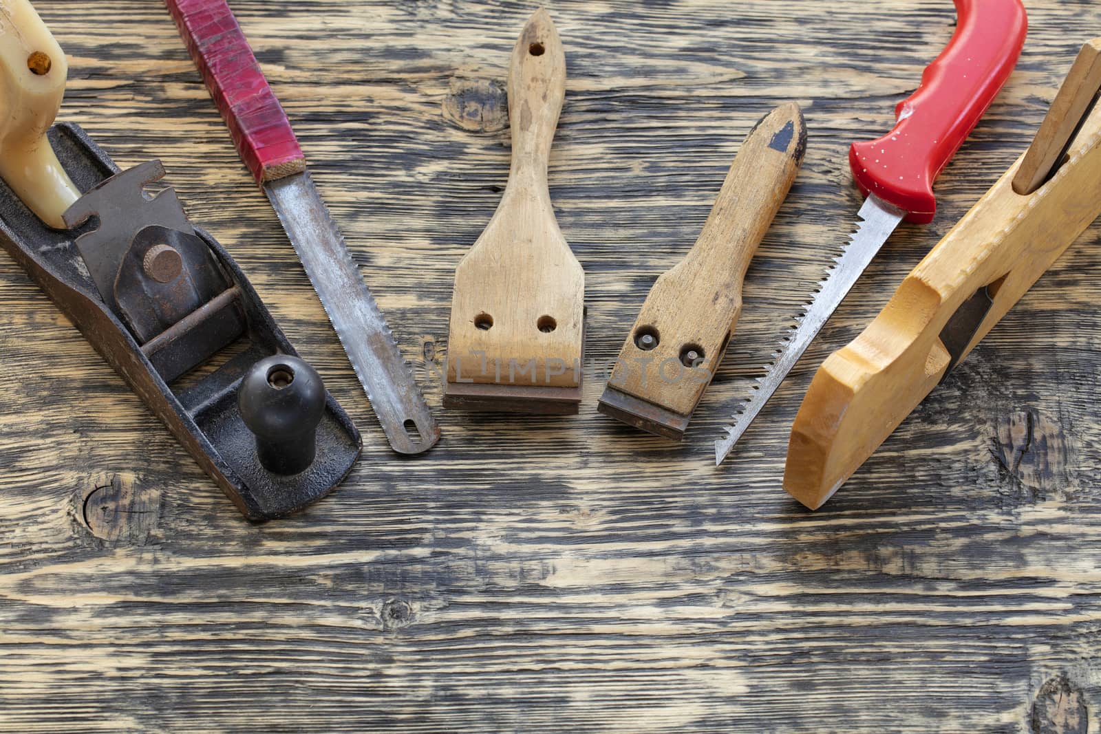 Old carpentry tools, planers, handsaws and cycles lie on a wooden table.