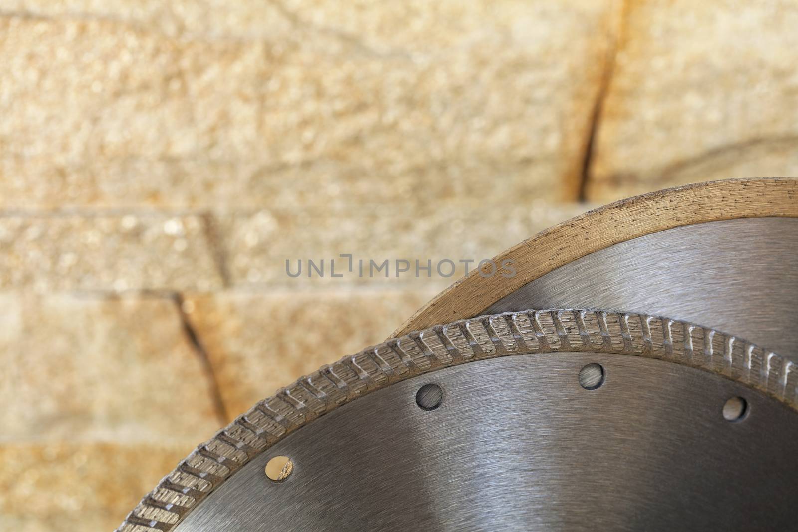 Segment of a diamond cutting disc on a background of orange-golden sandstone wall. by Sergii