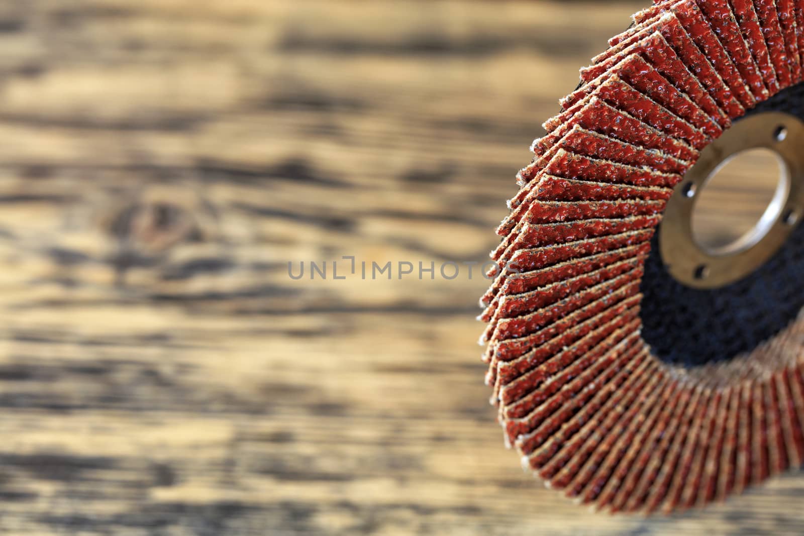 Part of the grinding disc for sanding wood and rusty metal on the background of an old wooden board in strong blur.