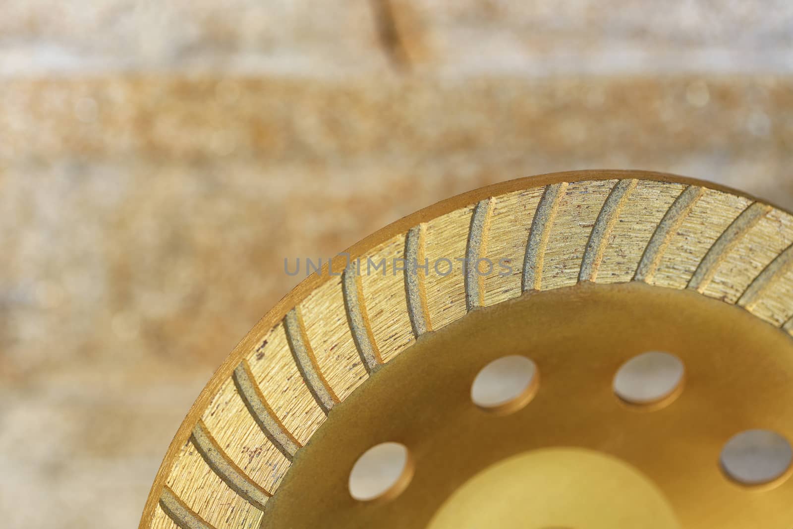 Part of the diamond grinding wheel on background an orange-golden sandstone wall. by Sergii