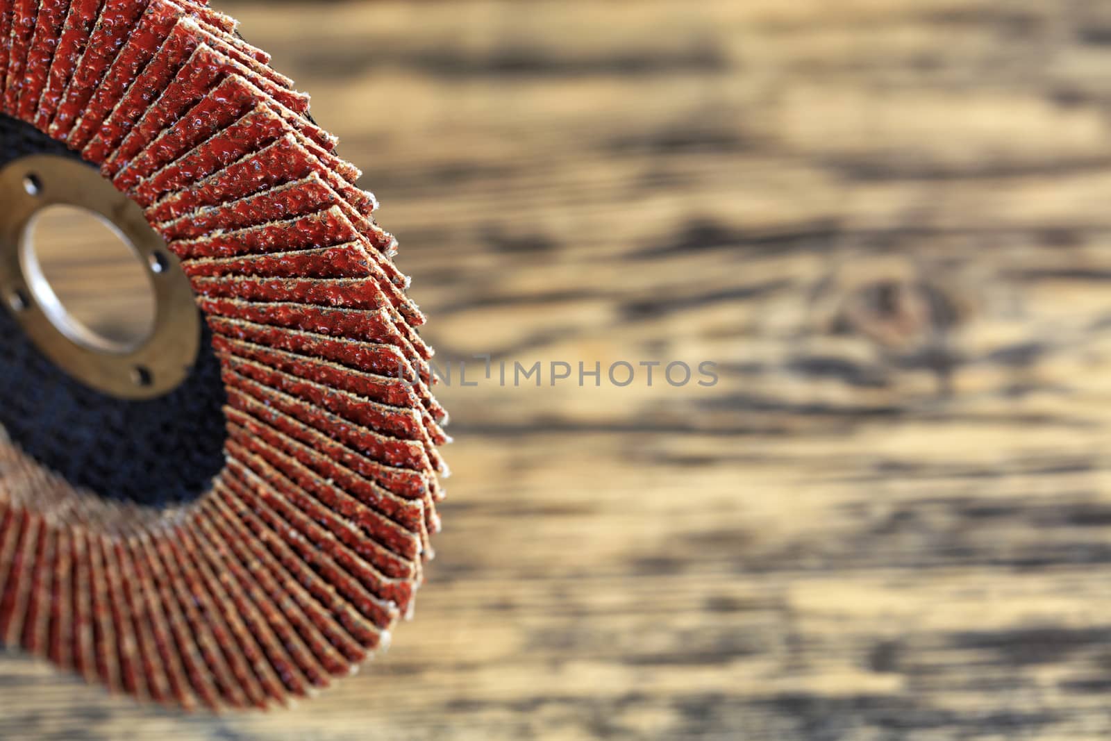 Part of the grinding disc for sanding wood and rusty metal on the background of an old wooden board in strong blur.