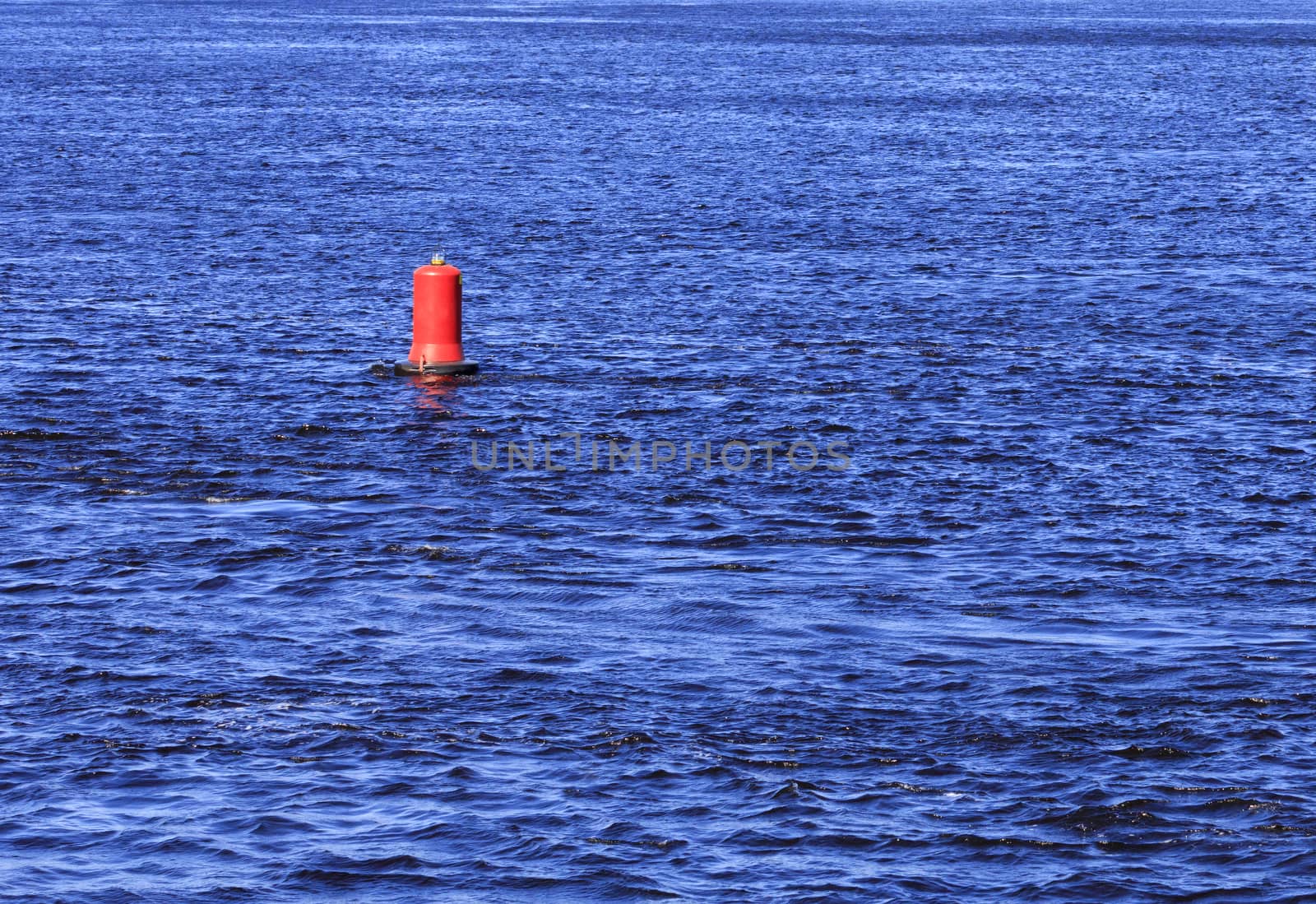 View of the blue waters of the river and the red buoy, which sways on the waves.