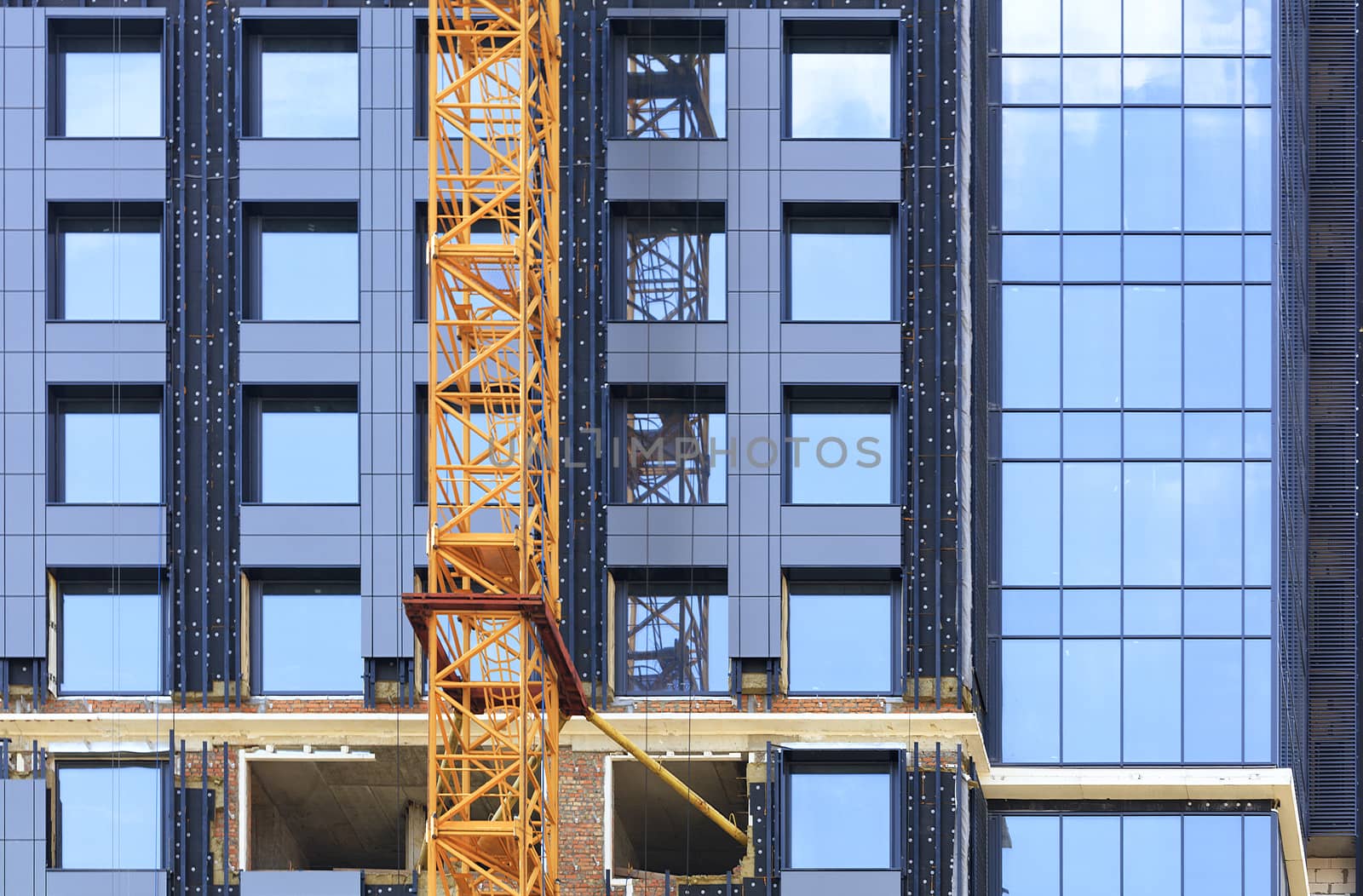 Facade and crane near a modern concrete building under construction. by Sergii