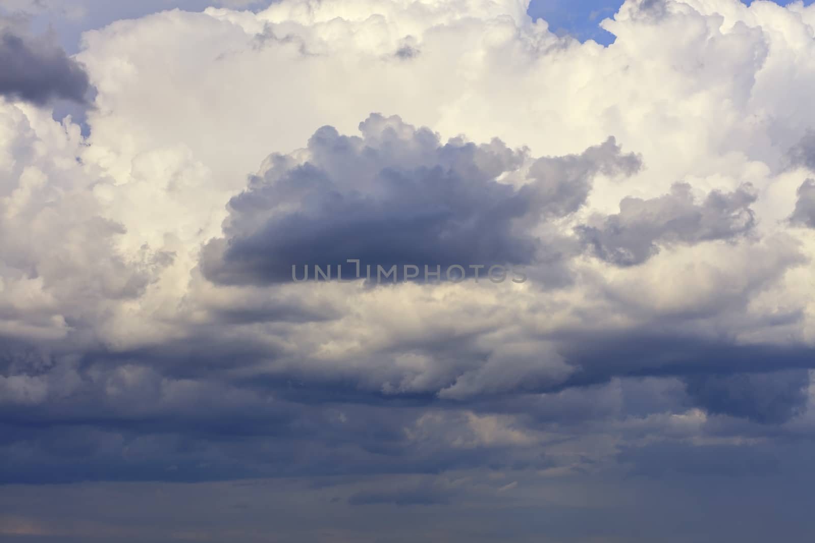 Thunderclouds float in the sky, gathering together and hide the blue sky.