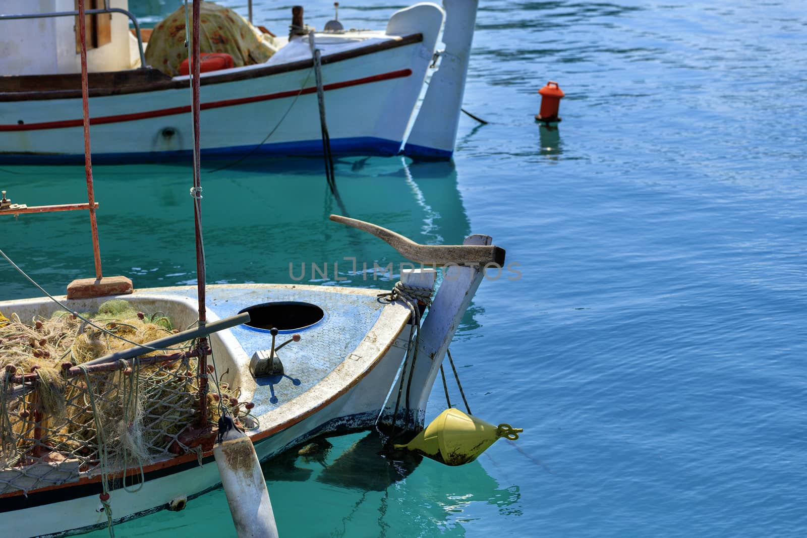 Fishing schooners with fishing nets on board are anchored in the clear waters of the Ionian Sea. Loutraki, Corinth, Greece.