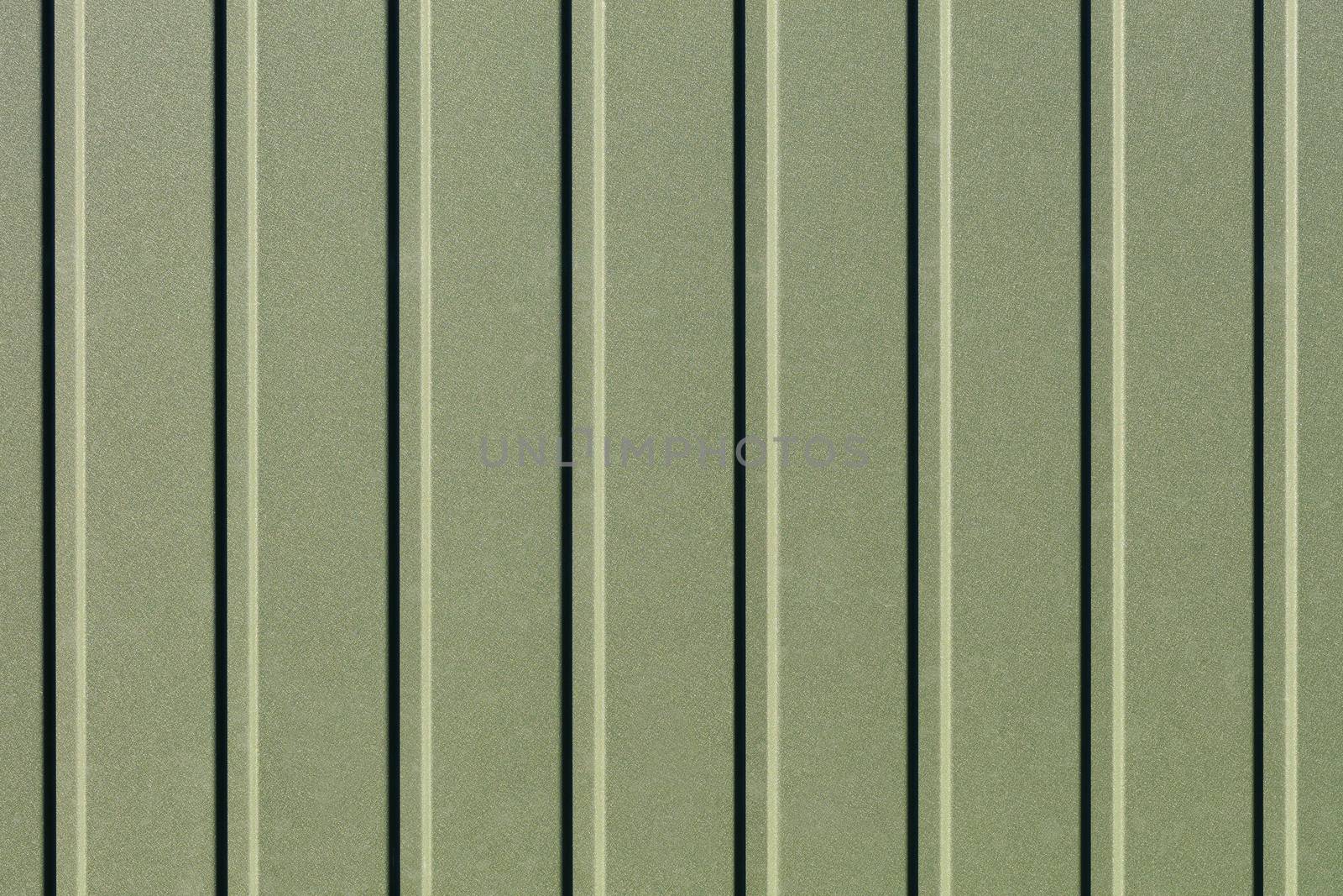Greenery metallic fence made of corrugated steel sheet with vertical guides. Corrugated green iron sheet background close up.