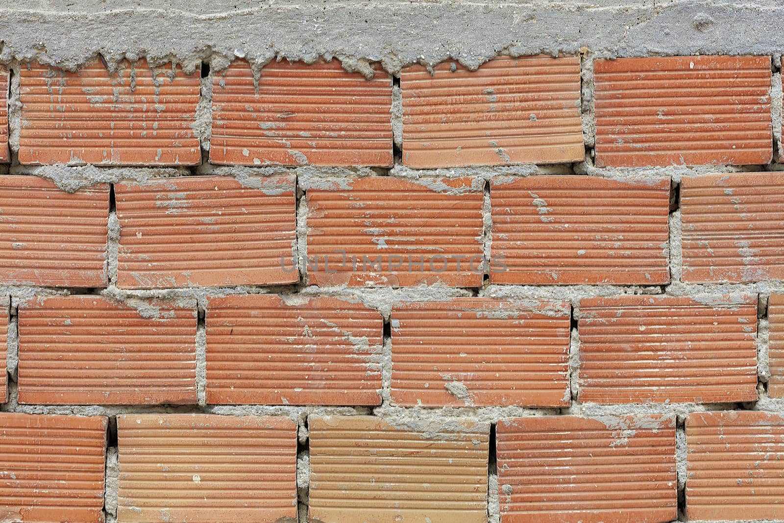 The pronounced texture of corpulent brick on the wall with a cement seam with cement hat. by Sergii