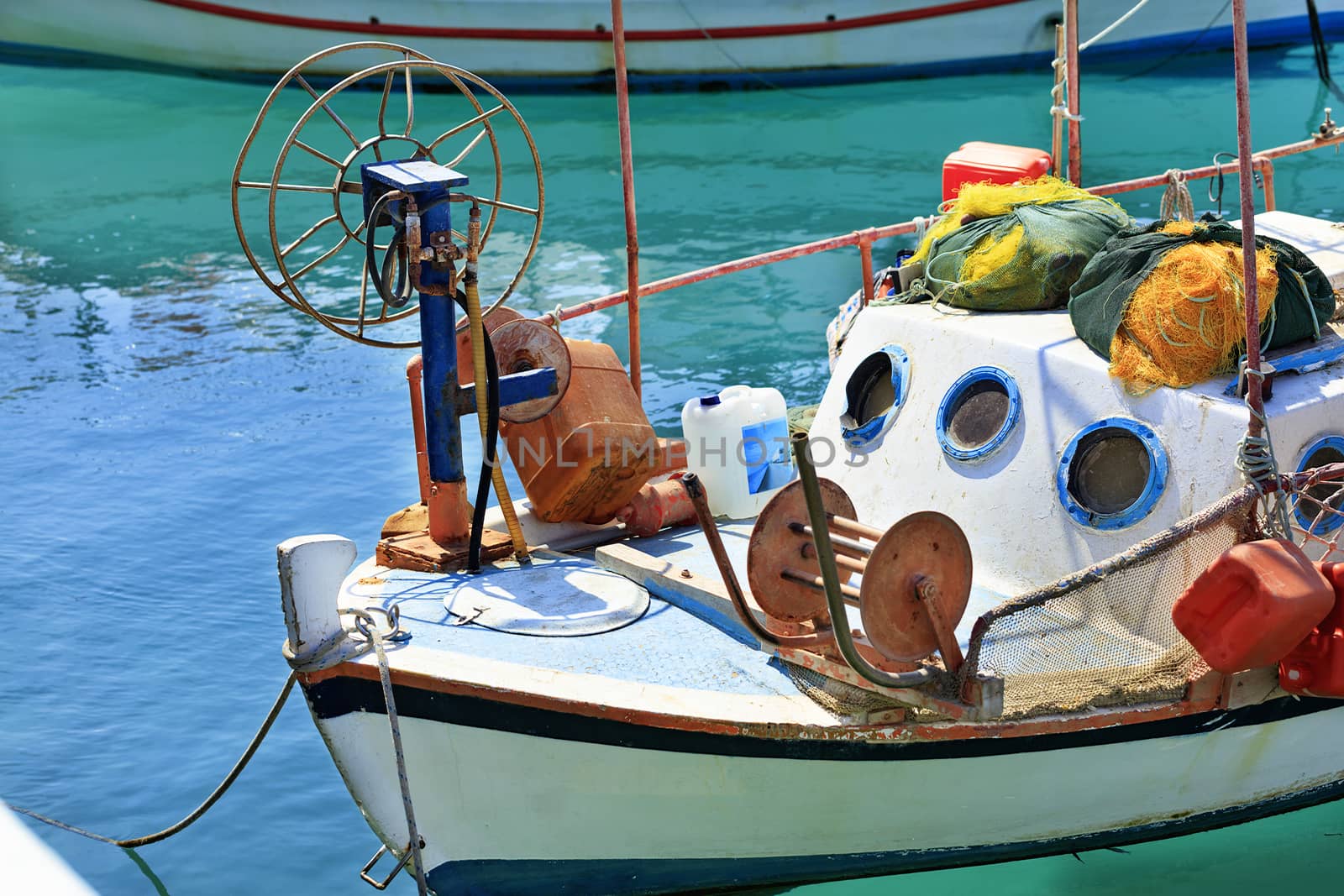 A fishing boat with fishing nets is anchored in the clear waters of the Ionian Sea. Loutraki, Corinth, Greece.