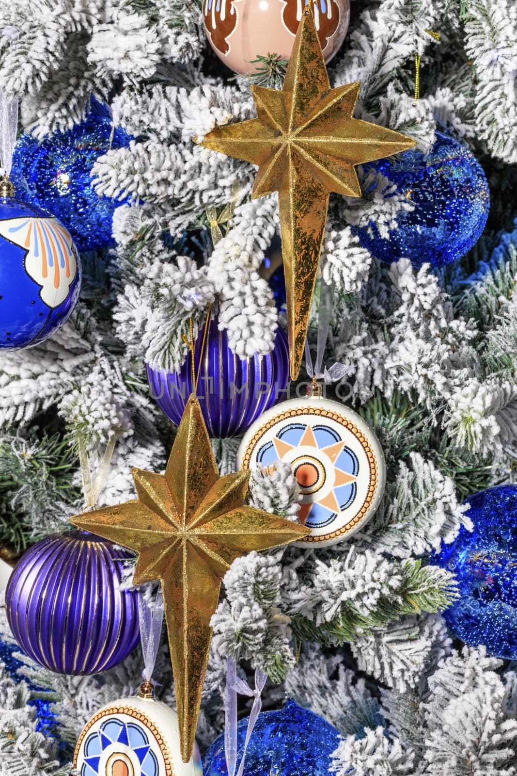 Collection of gold stars, blue Christmas balls, baubles for the Christmas tree, a spheres on the snowy branches of the Christmas tree.