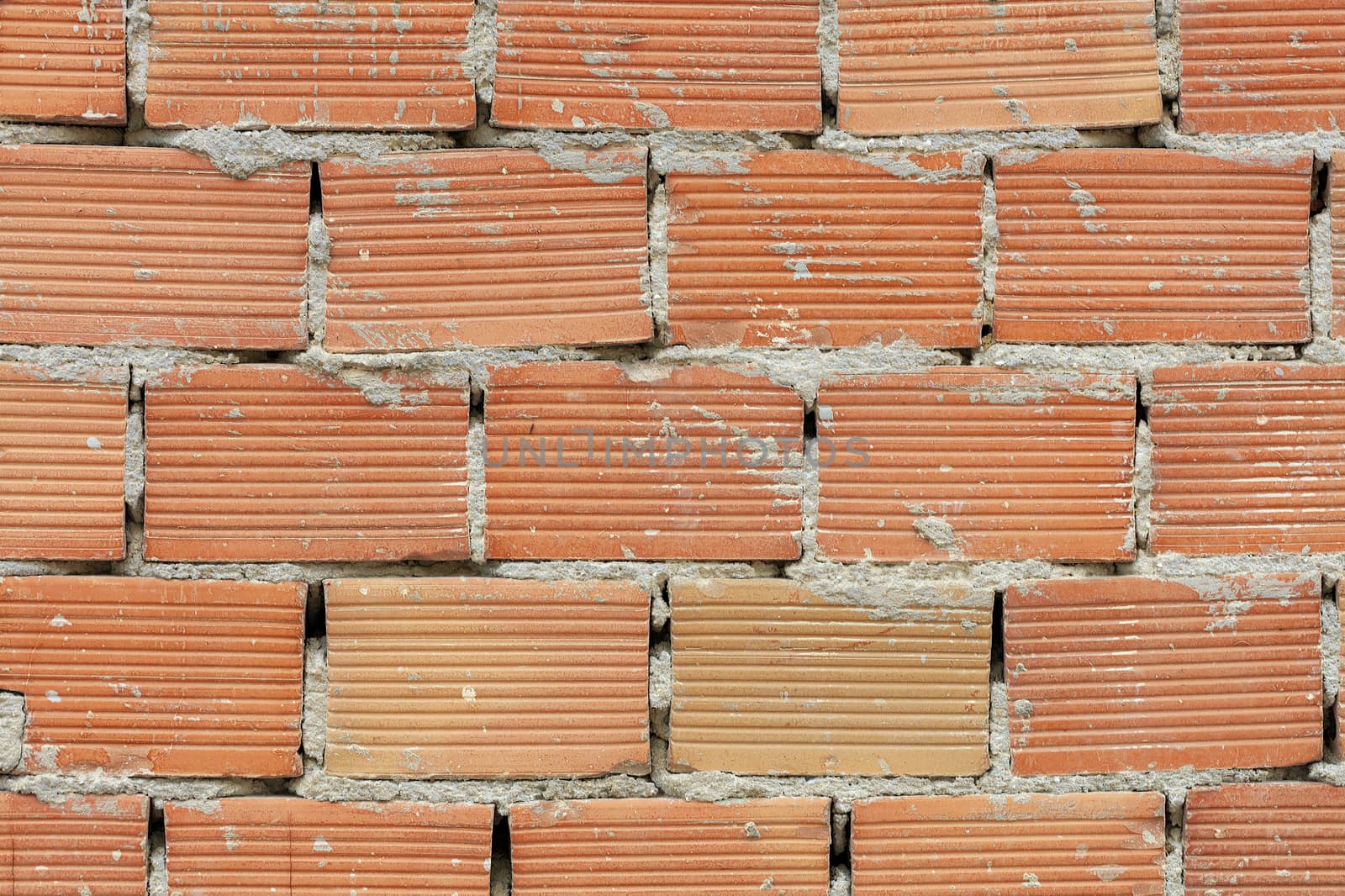 The new corpulent brick wall has an orange color and a horizontal texture with a cement seam.