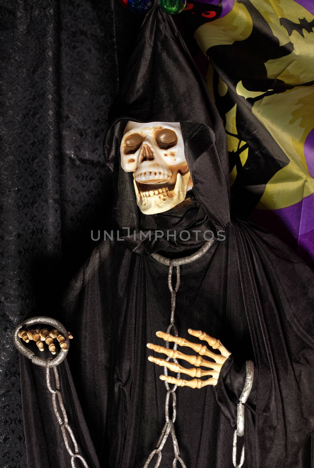 Halloween, doll Death in a black hoodie and a hood on the head with metal chains on the neck and arms.