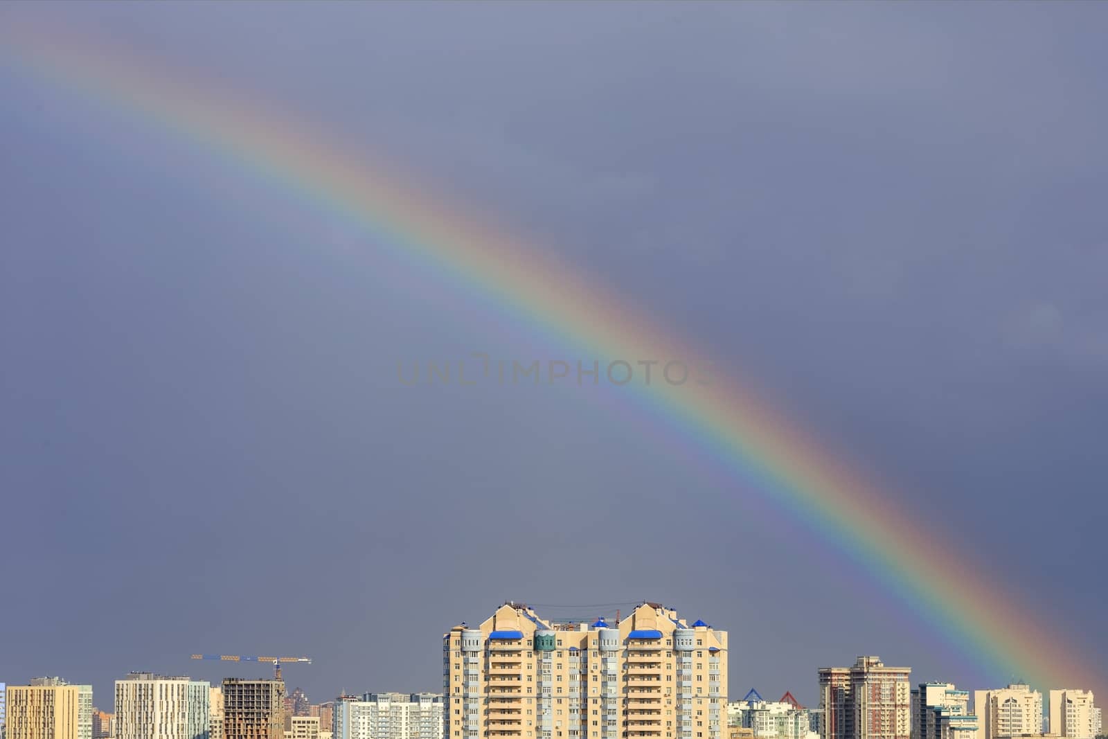 Rainbow in the sky above the city after a thunderstorm. by Sergii