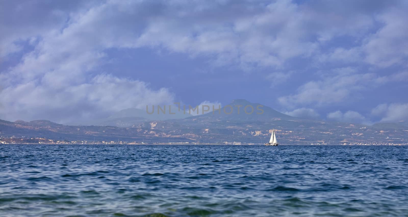 The silhouette of a sailing yacht on the horizon in the morning sea haze. by Sergii