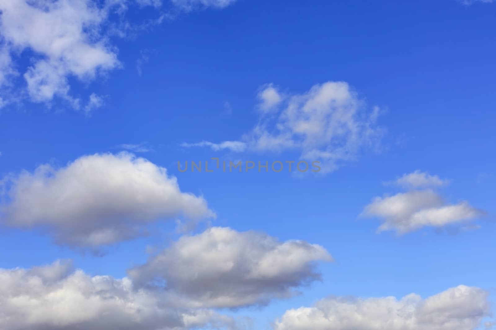 Blue sky background with the texture of white and fluffy, fun clouds.