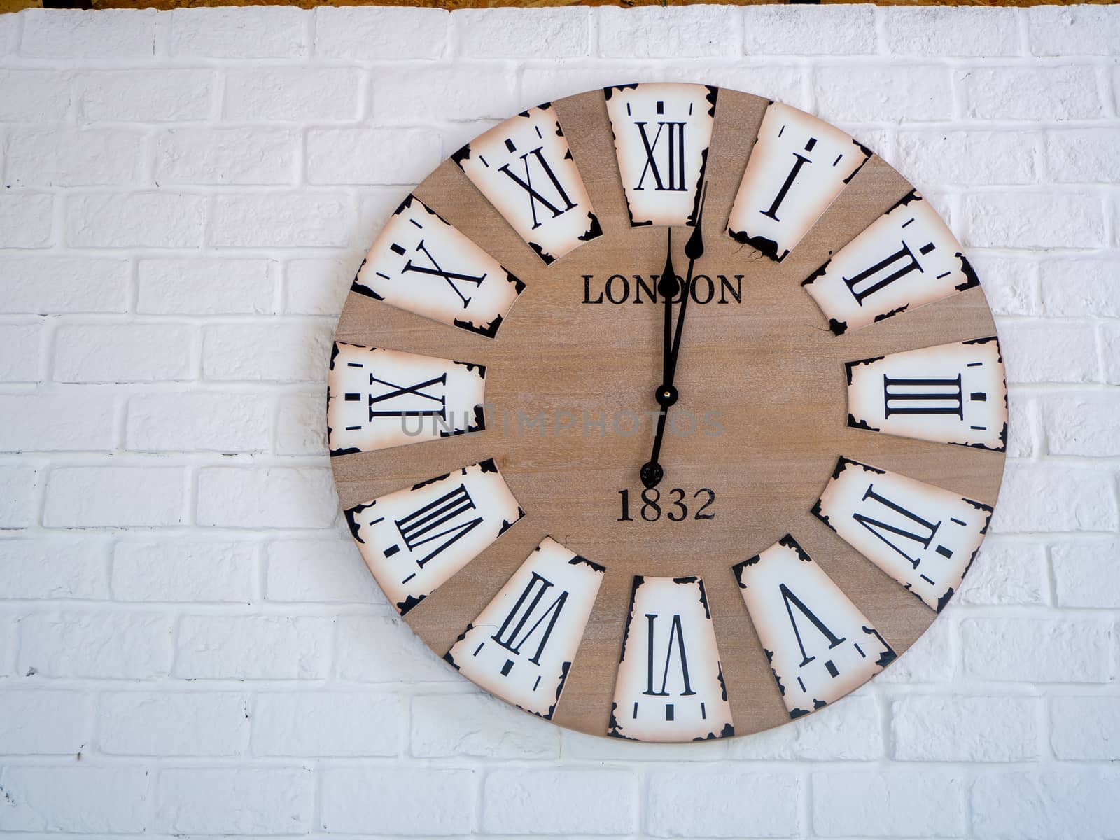 retro wall clock distressed and weather worn with Roman numerals on a wall