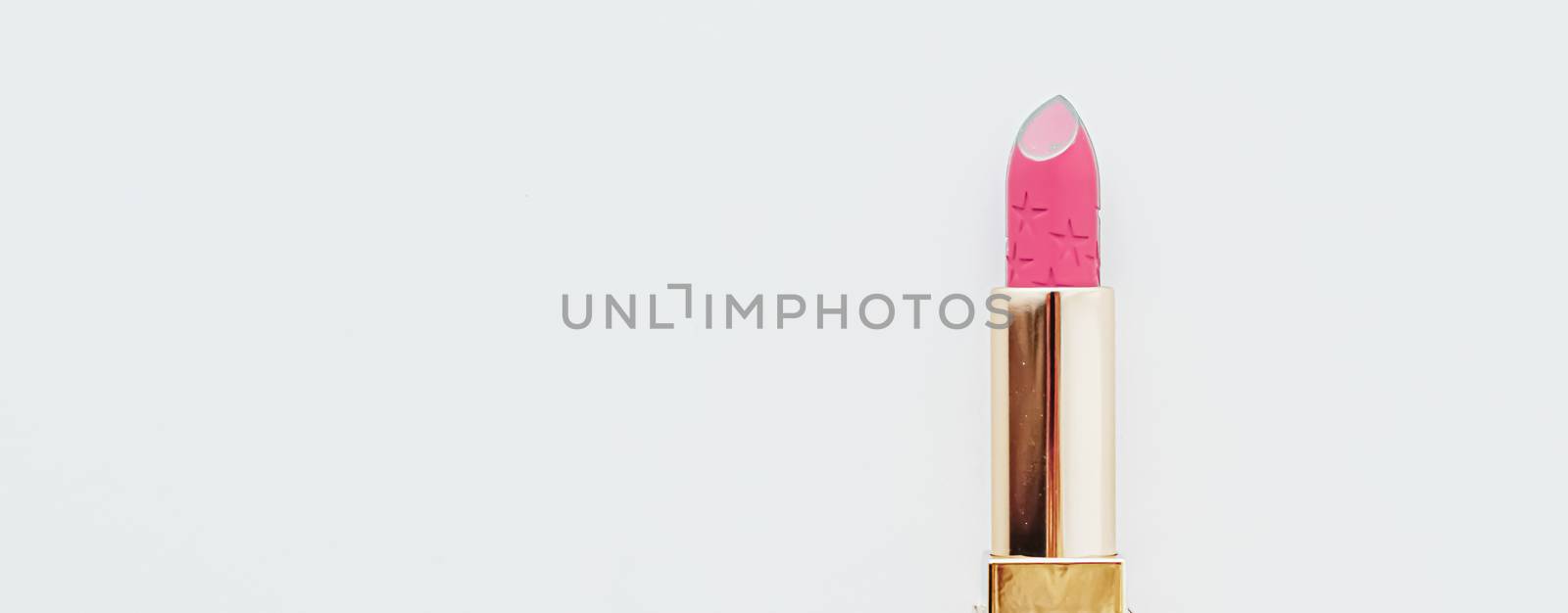 Luxury lipstick in a golden tube on white marble background, make-up and cosmetics concept