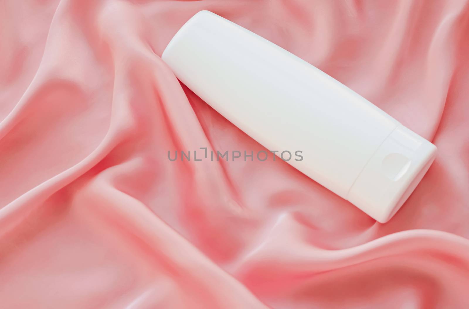 Blank label cosmetic container bottle as product mockup on pink silk background, hygiene and healthcare