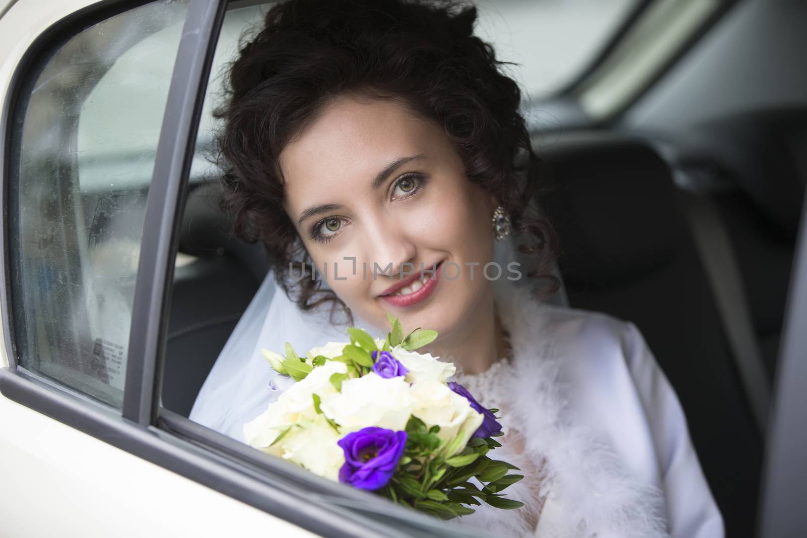 Portrait of a bride in a car with a bouquet