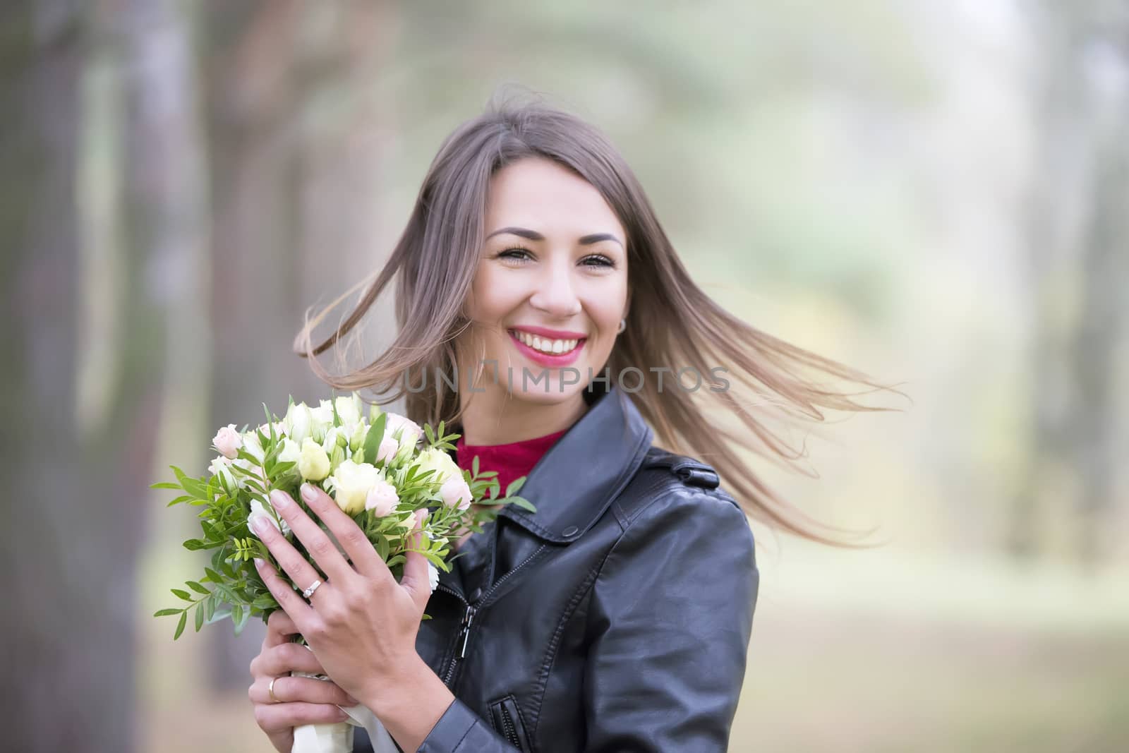 Beautiful woman with a bouquet of flowers in the forest